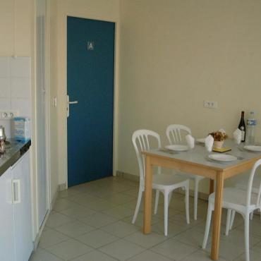 Intérieur d'un gîte : coin repas avec table, chaises et kitchenette