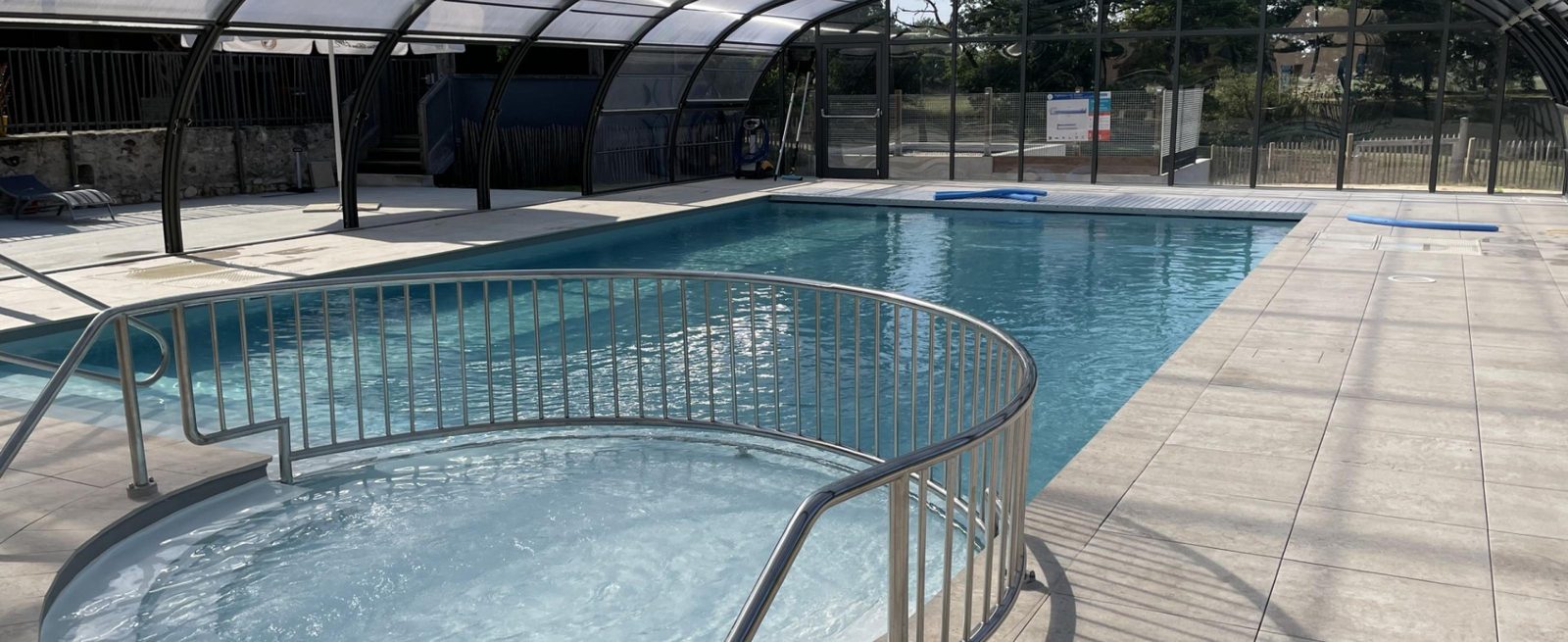 Bassin de la piscine couverte et chauffée sous sa structure vitrée