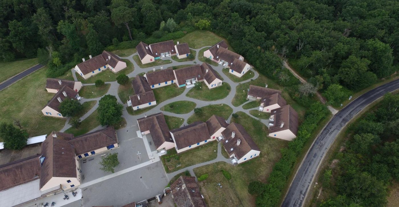 Vue aérienne du village vacances et de ses gîtes disposés en hameau dans la forêt